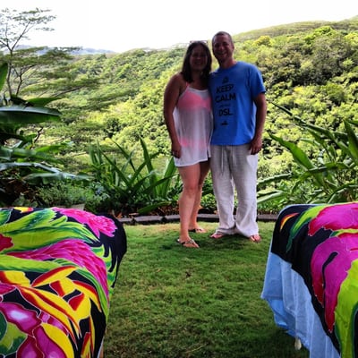 A couple standing between two massage tables in a lush green Kauaʻi valley